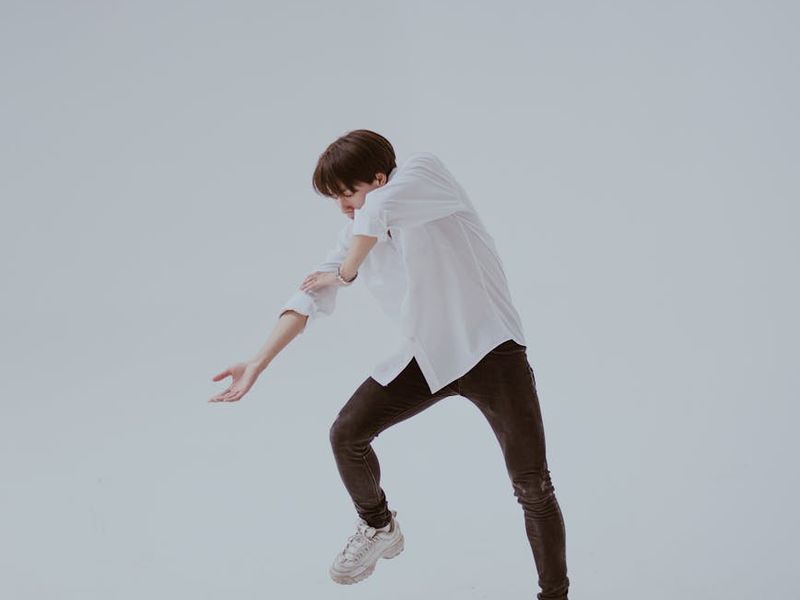 Person in a dynamic cardio movement pose in a minimalist studio.